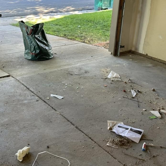 Driveway and garage entry scattered with construction scraps and litter