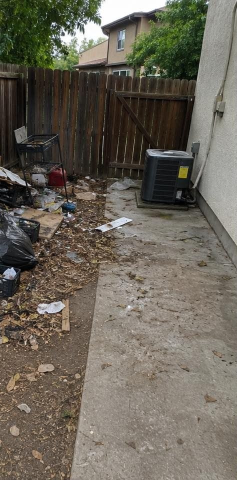 Side yard buried in bagged trash, scattered debris, and yard waste before ParoJunks cleared it