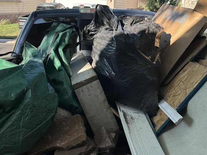 Pickup bed loaded to the rails with bagged debris, lumber, and old building material